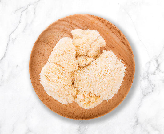 A wooden plate holding fresh lion's mane mushrooms on an elegant granite countertop - lion's mane mushroom extract can be purchased online for delivery from Mogu Mushrooms.