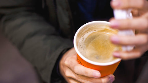 A person opening a cup of coffee, likely preparing to add organic reishi mushroom powder as a supplement. The image highlights how easily organic reishi mushroom extract can be incorporated into daily beverages like coffee for a simple wellness boost.