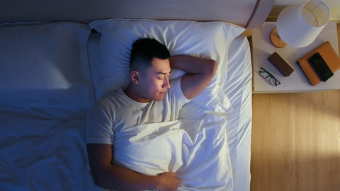 Man peacefully sleeping in bed with a serene expression, showcasing the potential benefits of Reishi for sleep and relaxation.